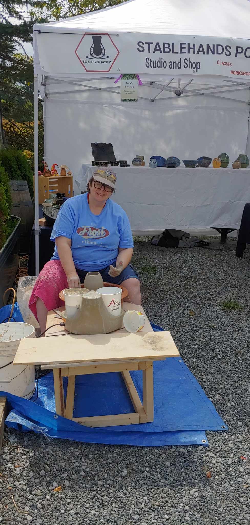 Em demonstrating pottery at a market, summer 2024